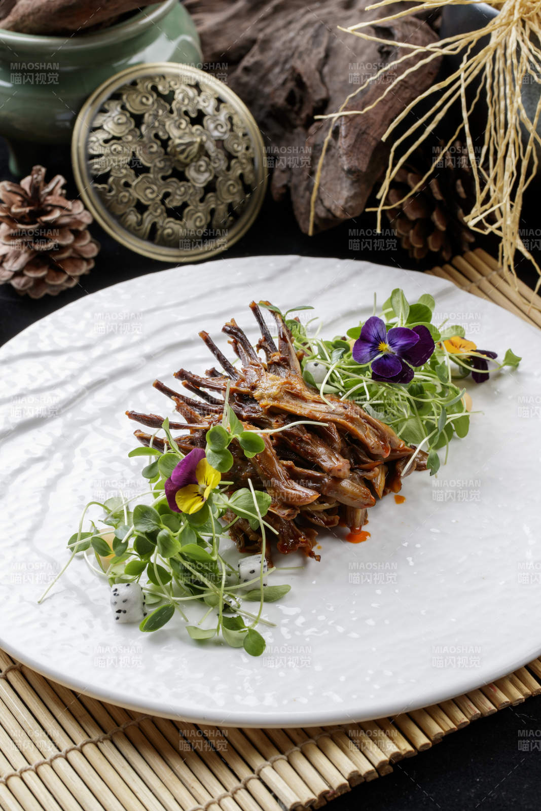 寿司帘上的圆瓷盘装的香辣鸭舌