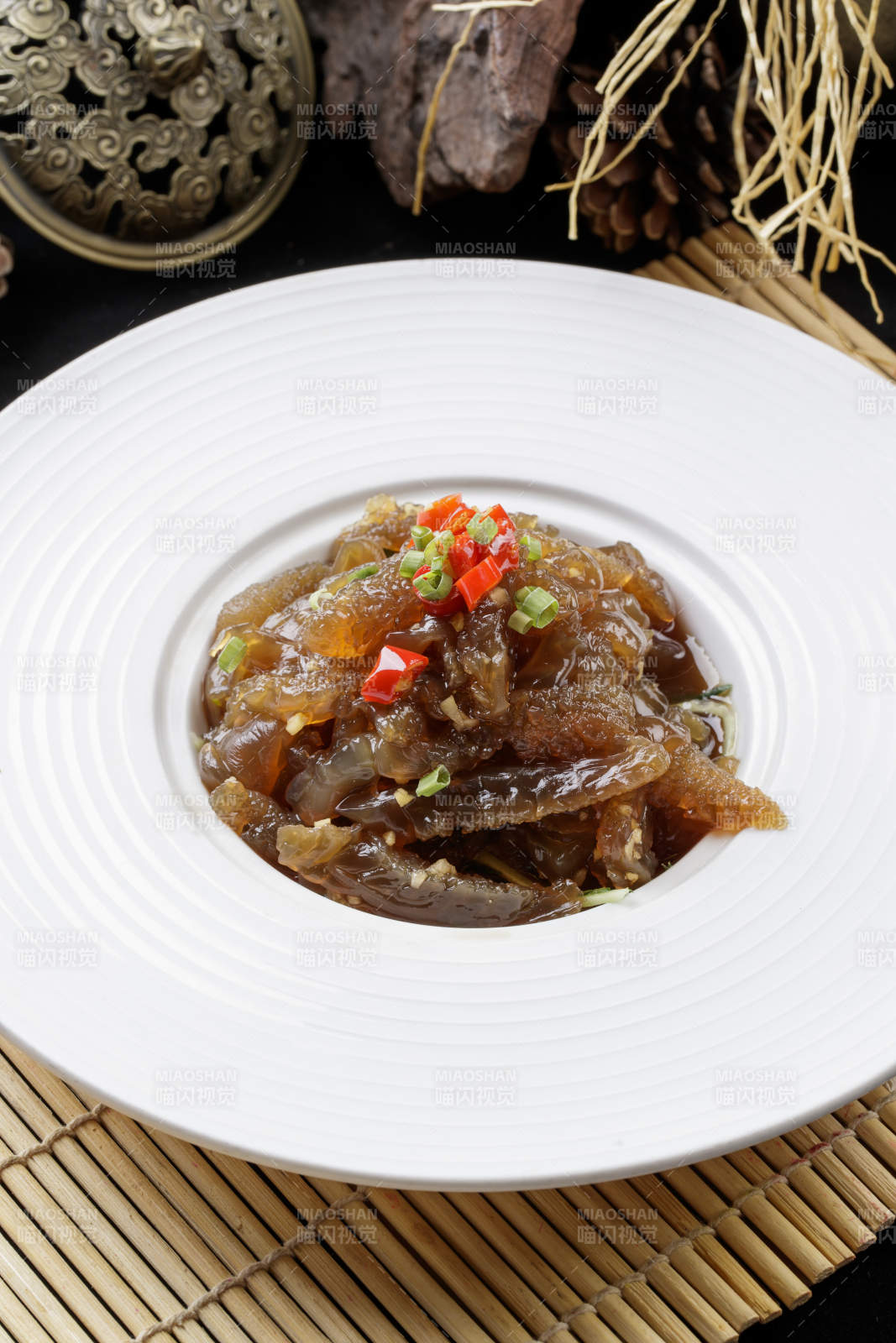 寿司帘上的圆瓷盘装的老醋蛰头