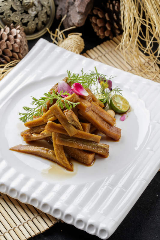 寿司帘上的方瓷盘装的暴腌萝卜条