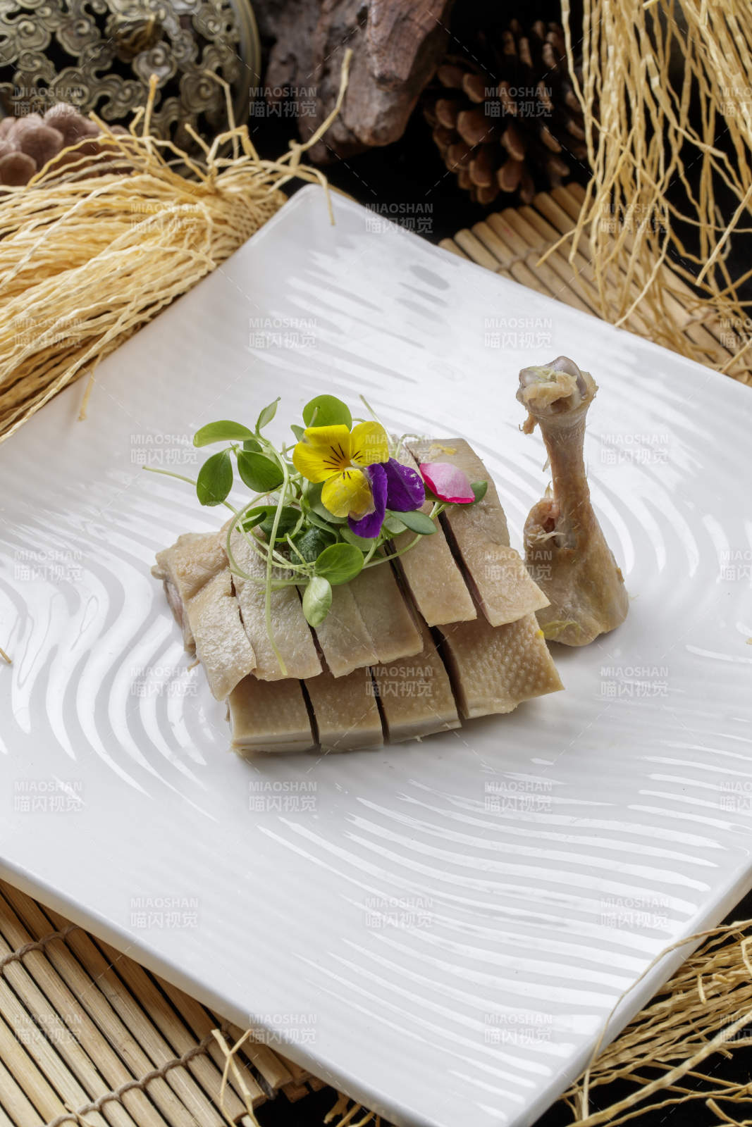 寿司帘上的方瓷盘装的盐水鸡腿图片