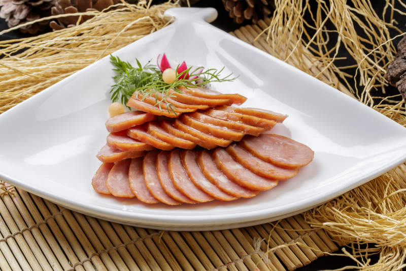 寿司帘上的扇形瓷盘装的自制蒜味香肠