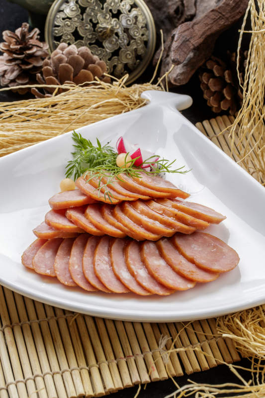 寿司帘上的扇形瓷盘装的自制蒜味香肠