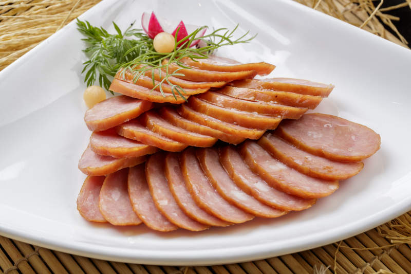 寿司帘上的扇形瓷盘装的自制蒜味香肠