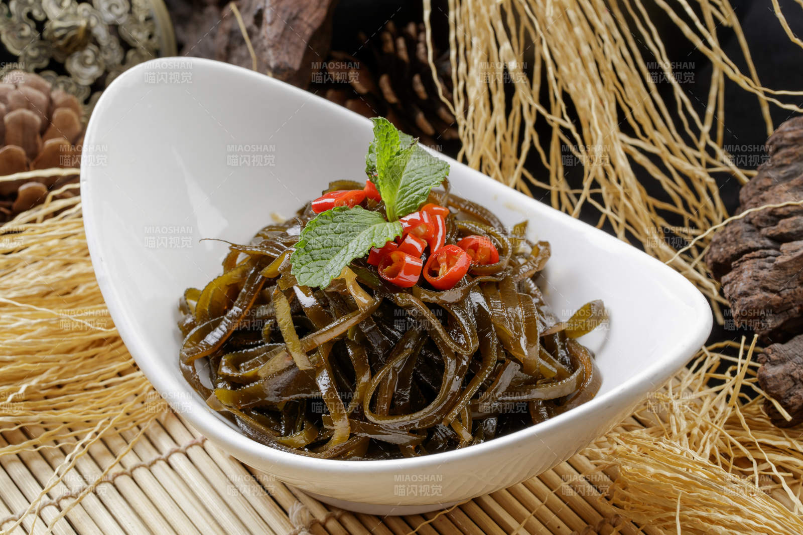 壽司簾上的元寶瓷盤裝的涼拌海帶絲