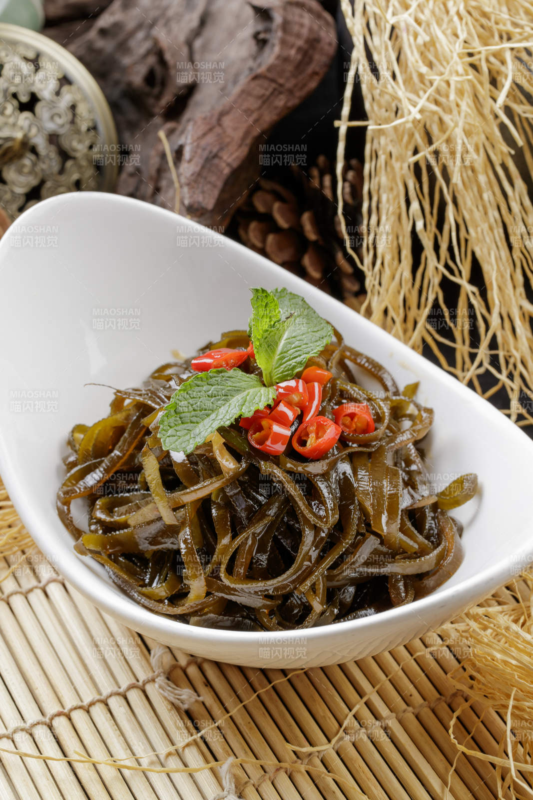 壽司簾上的元寶瓷盤裝的涼拌海帶絲