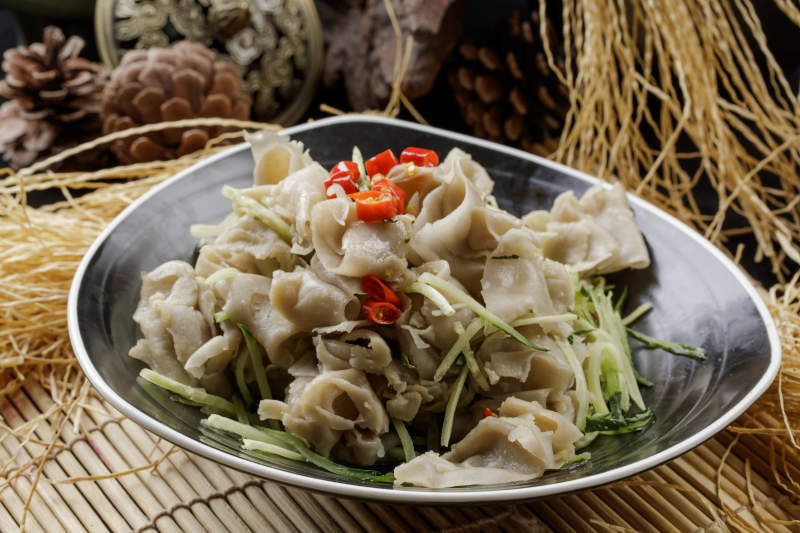 寿司帘上的黑瓷碗装的一品凉拌莜面窝窝