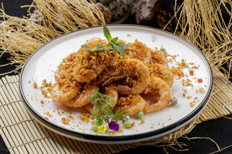 壽司簾上的圓瓷盤裝的酥炸大明蝦