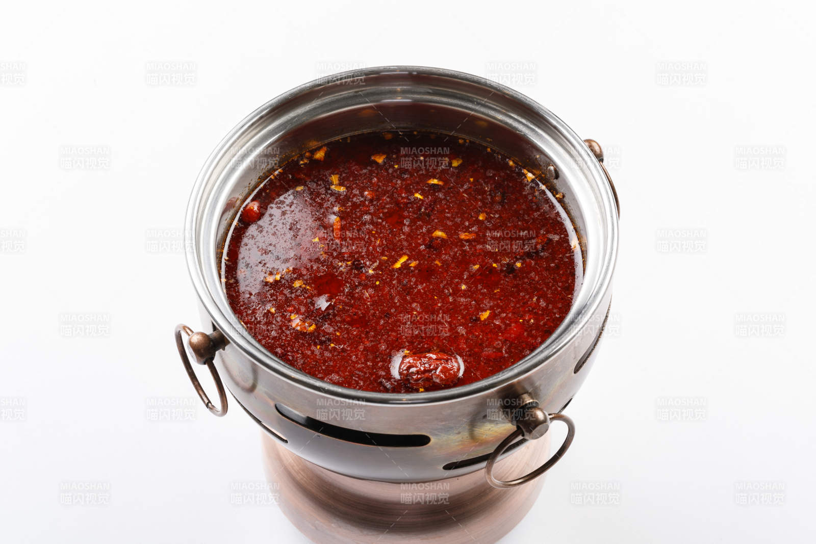 白色背景上的小火锅装的红油麻辣锅底