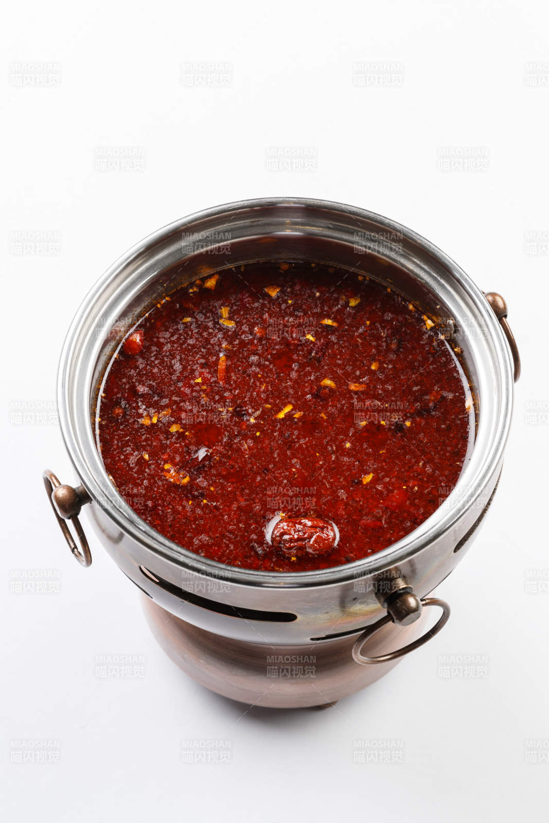 白色背景上的小火锅装的红油麻辣锅底