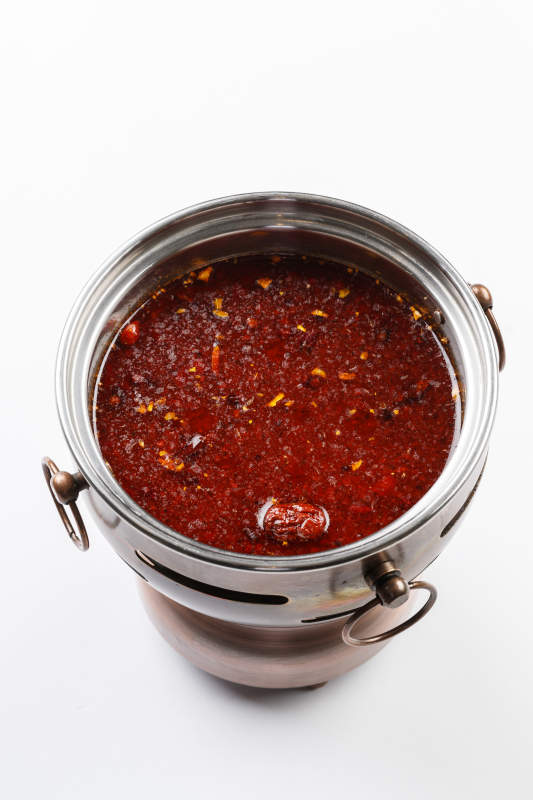 白色背景上的小火锅装的红油麻辣锅底