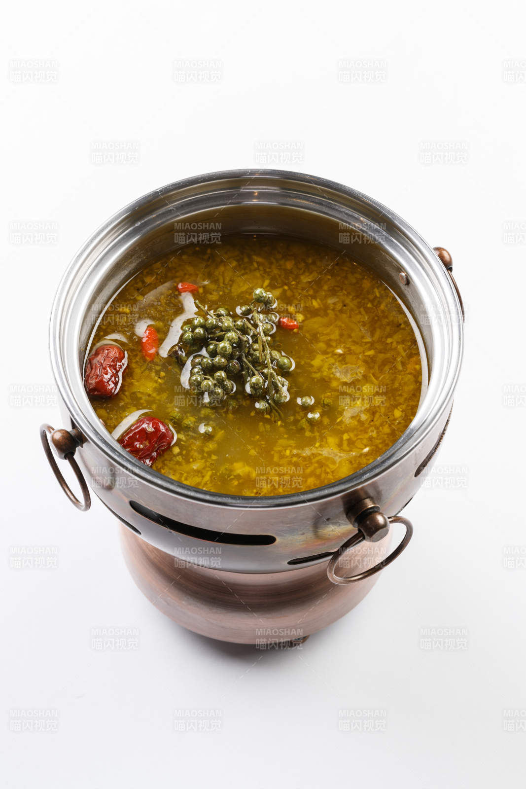 白色背景上的小火锅装的牛油藤椒酸辣锅底
