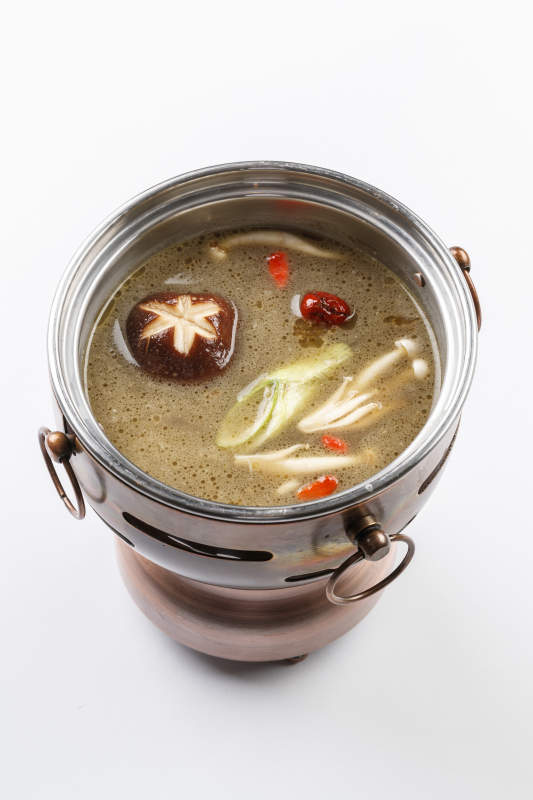 白色背景上的小火锅装的菌汤锅底