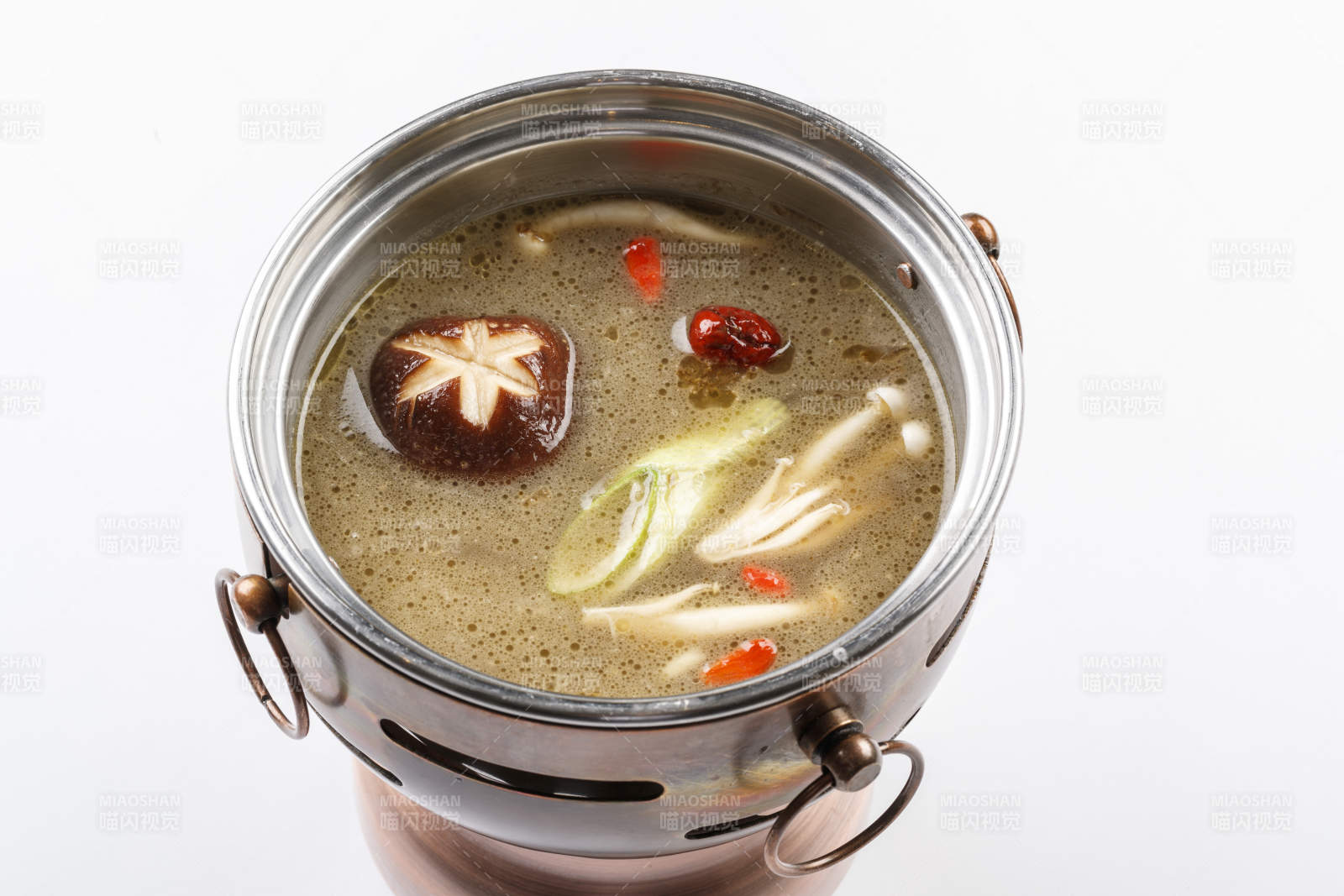 白色背景上的小火锅装的菌汤锅底
