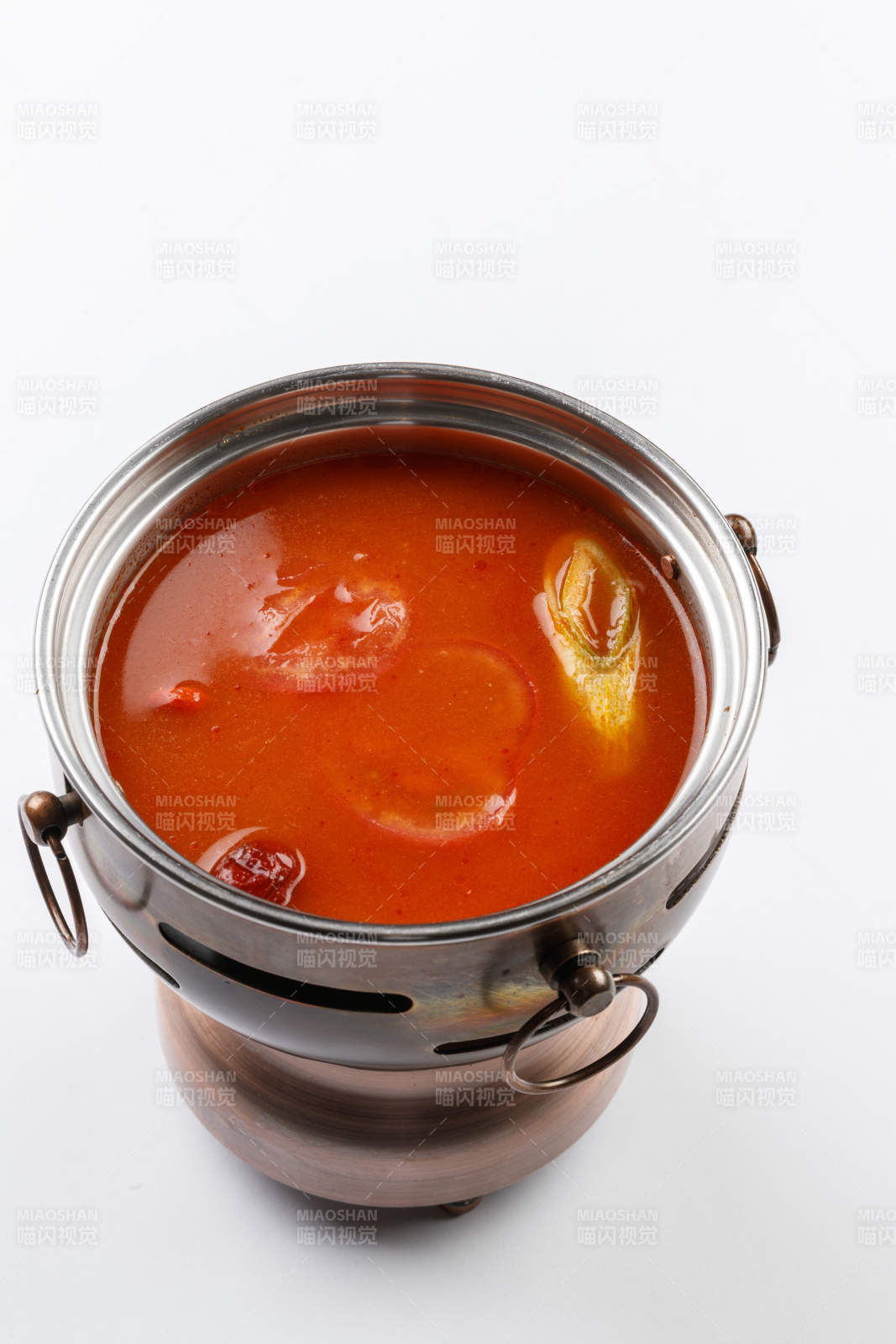 白色背景上的小火锅装的番茄锅底