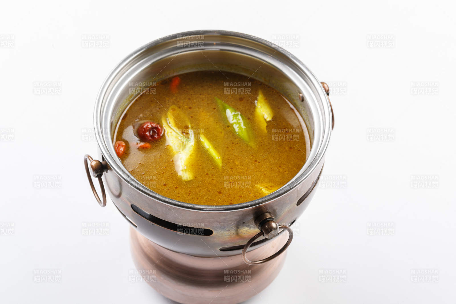 白色背景上的小火锅装的鸡汤锅底