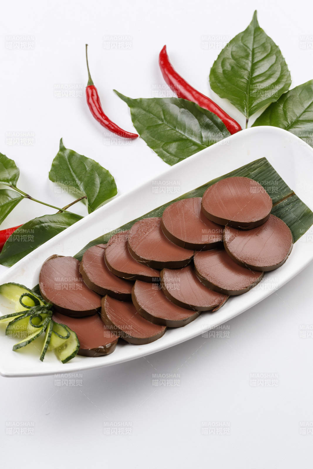 白色背景上的长瓷盘装的火锅食材鸭血图片