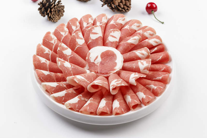 白色背景上的圓瓷盤裝的涮鍋食材肥牛片