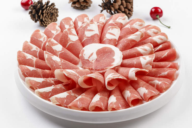 白色背景上的圓瓷盤裝的涮鍋食材肥牛片