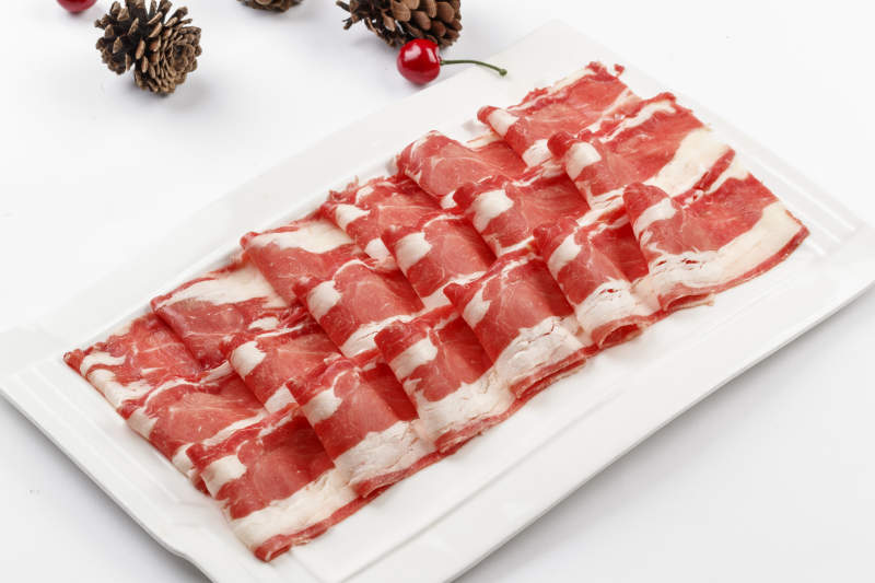 白色背景上的長瓷盤裝的涮肉食材羊肉片