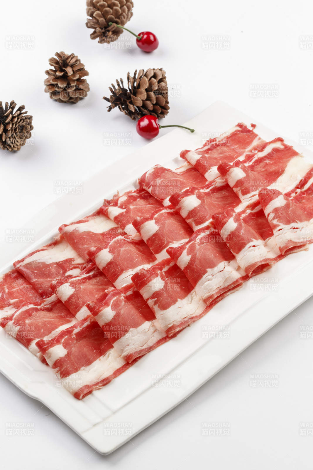 白色背景上的長瓷盤裝的涮肉食材羊肉片