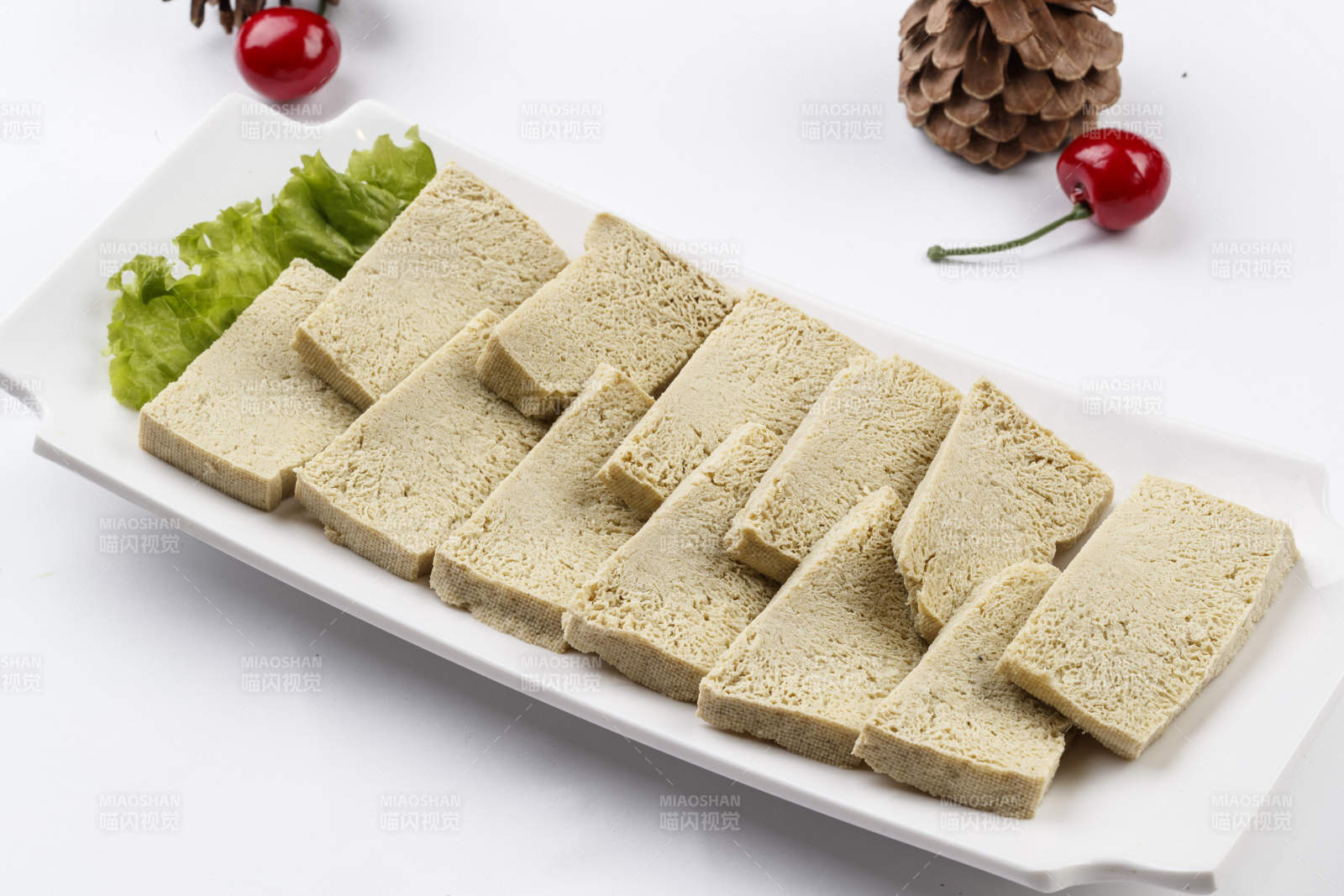 白色背景上的長瓷盤裝的火鍋食材凍豆腐