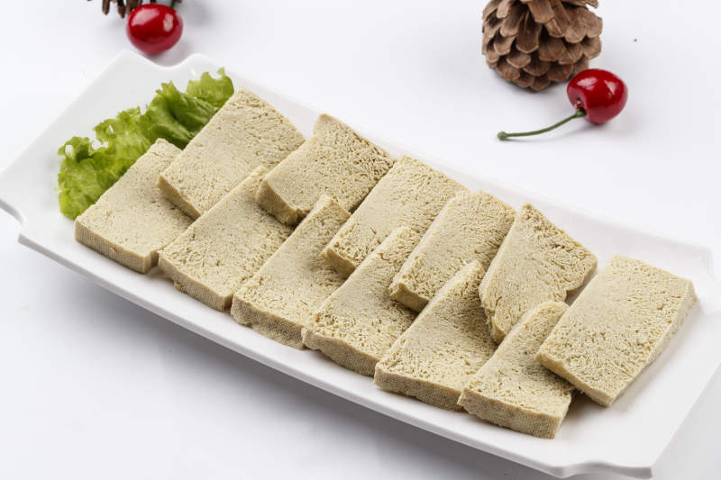 白色背景上的長瓷盤裝的火鍋食材凍豆腐