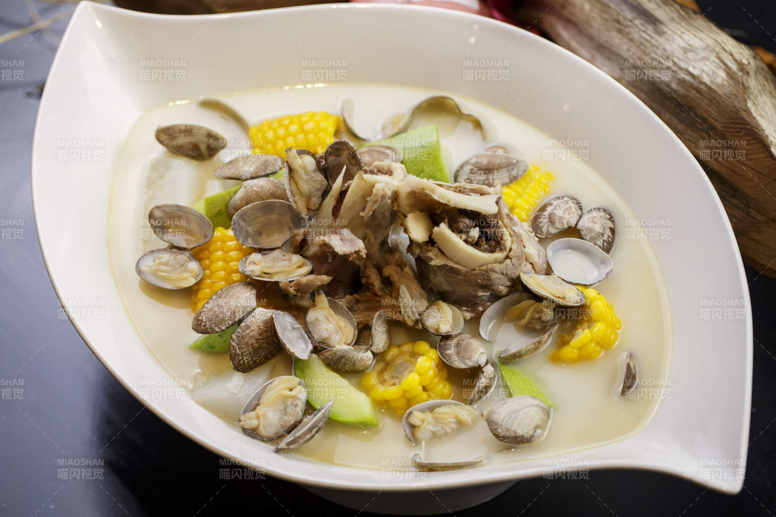 树叶形瓷盘装的奶汤棒骨花蛤炖时蔬图片