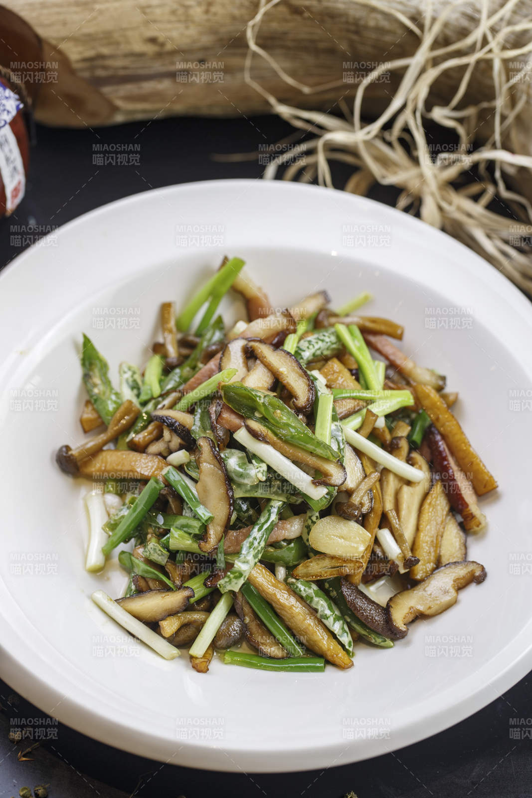 圓形白色瓷盤裝的臘肉小炒山珍菌