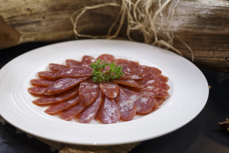 圆形白瓷盘装的川味甜腊肠