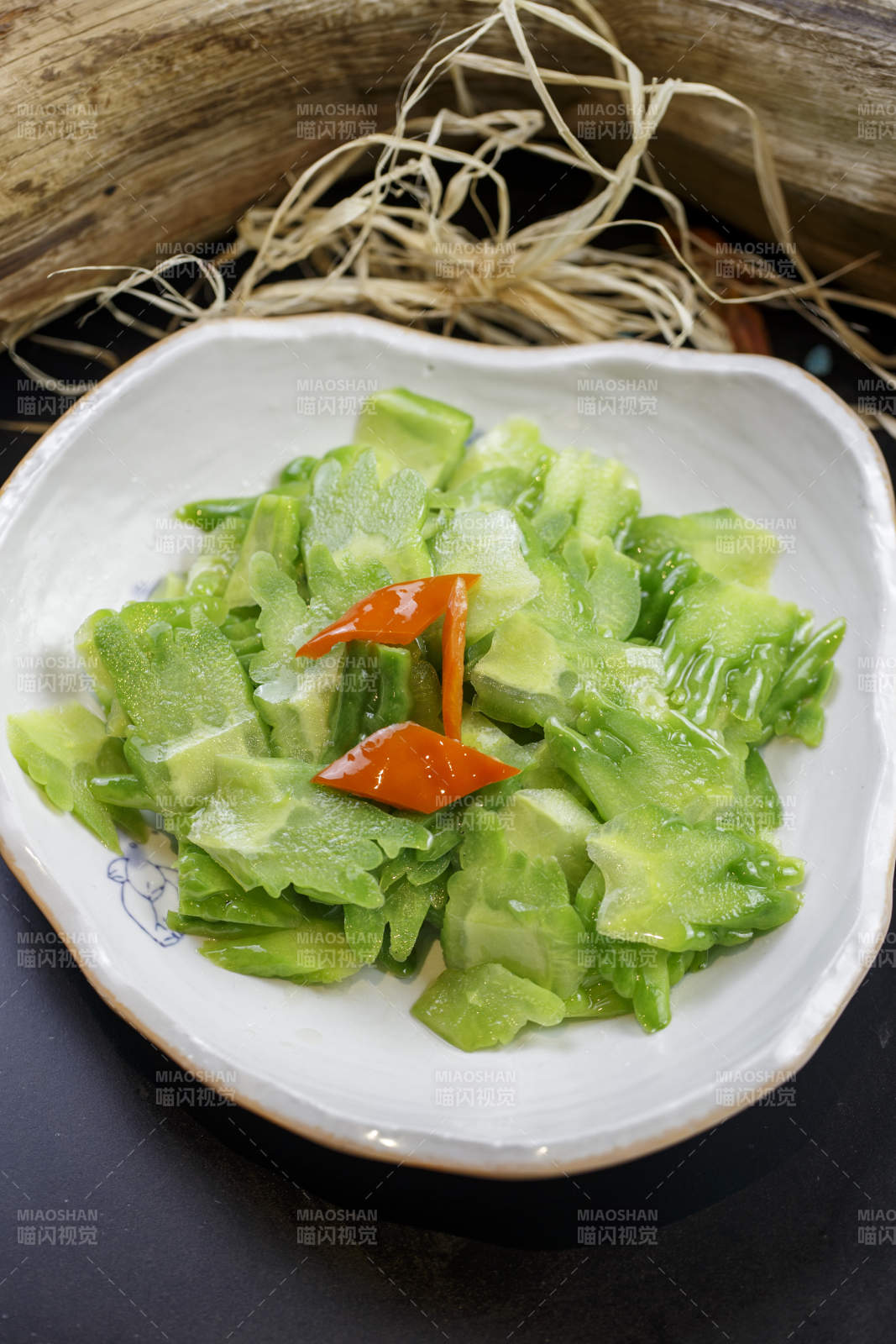 浪花边瓷盘装的炝炒苦瓜