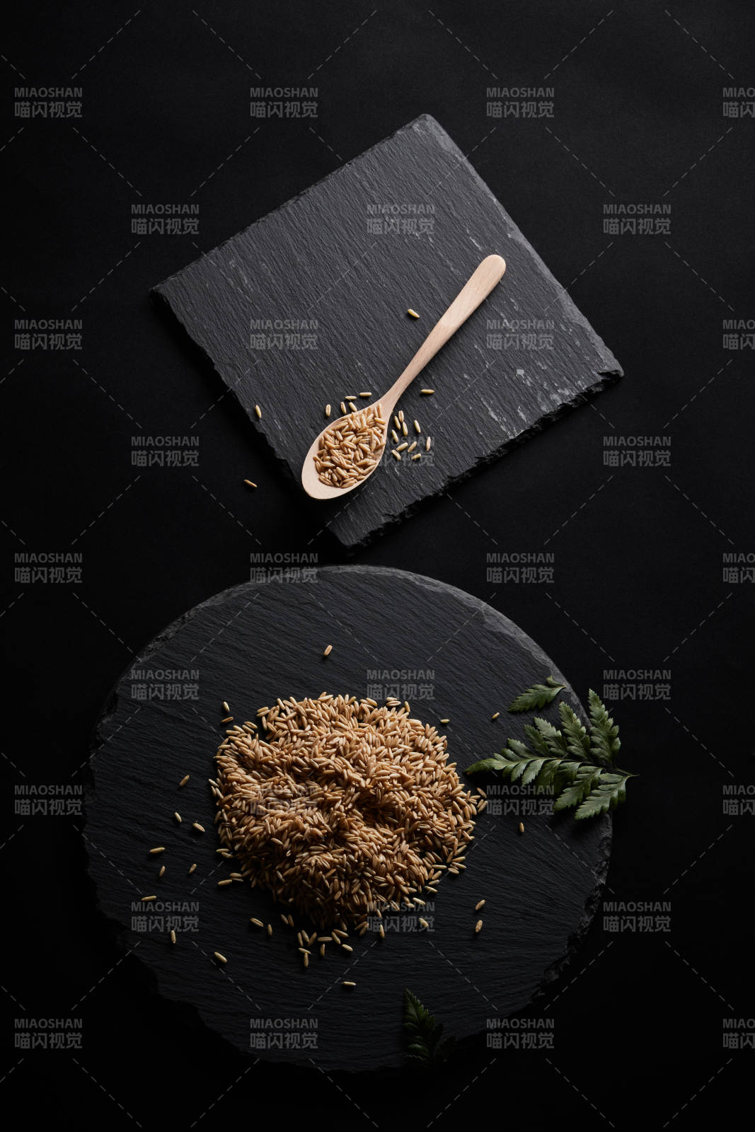 黑色青石板上的木質(zhì)勺子裝的燕麥米擺放在黑色背景中