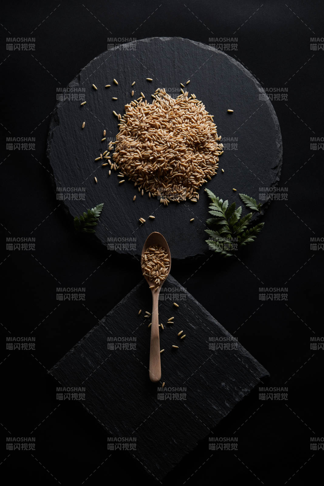 黑色青石板上的木质勺子装的燕麦米摆放在黑色背景中