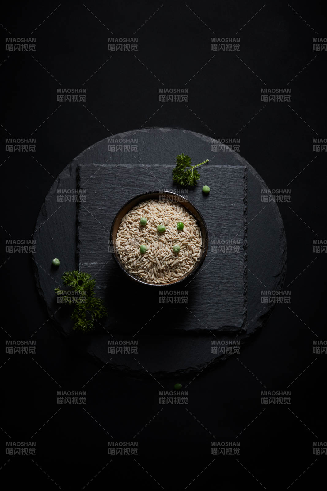 黑色青石板上的木质勺子装的燕麦米摆放在黑色背景中