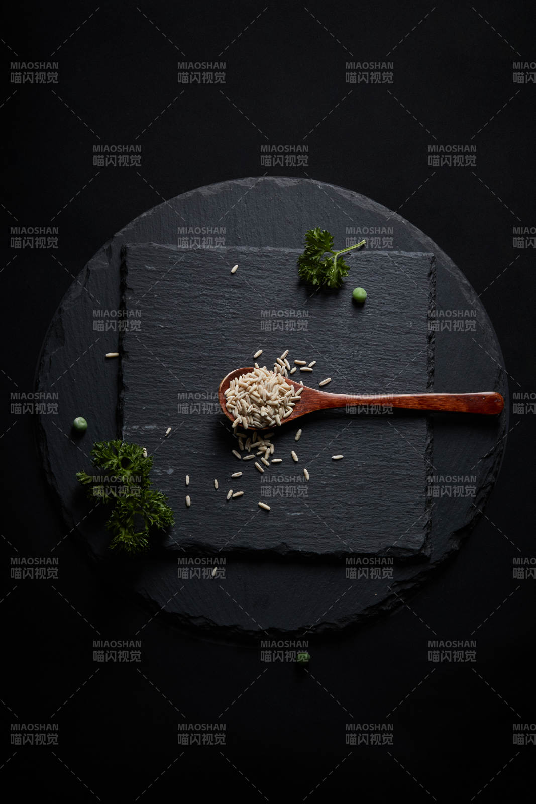 黑色青石板上的木質(zhì)勺子裝的燕麥米擺放在黑色背景中