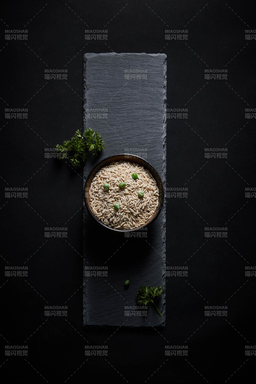 黑色青石板上的木质勺子装的燕麦米摆放在黑色背景中