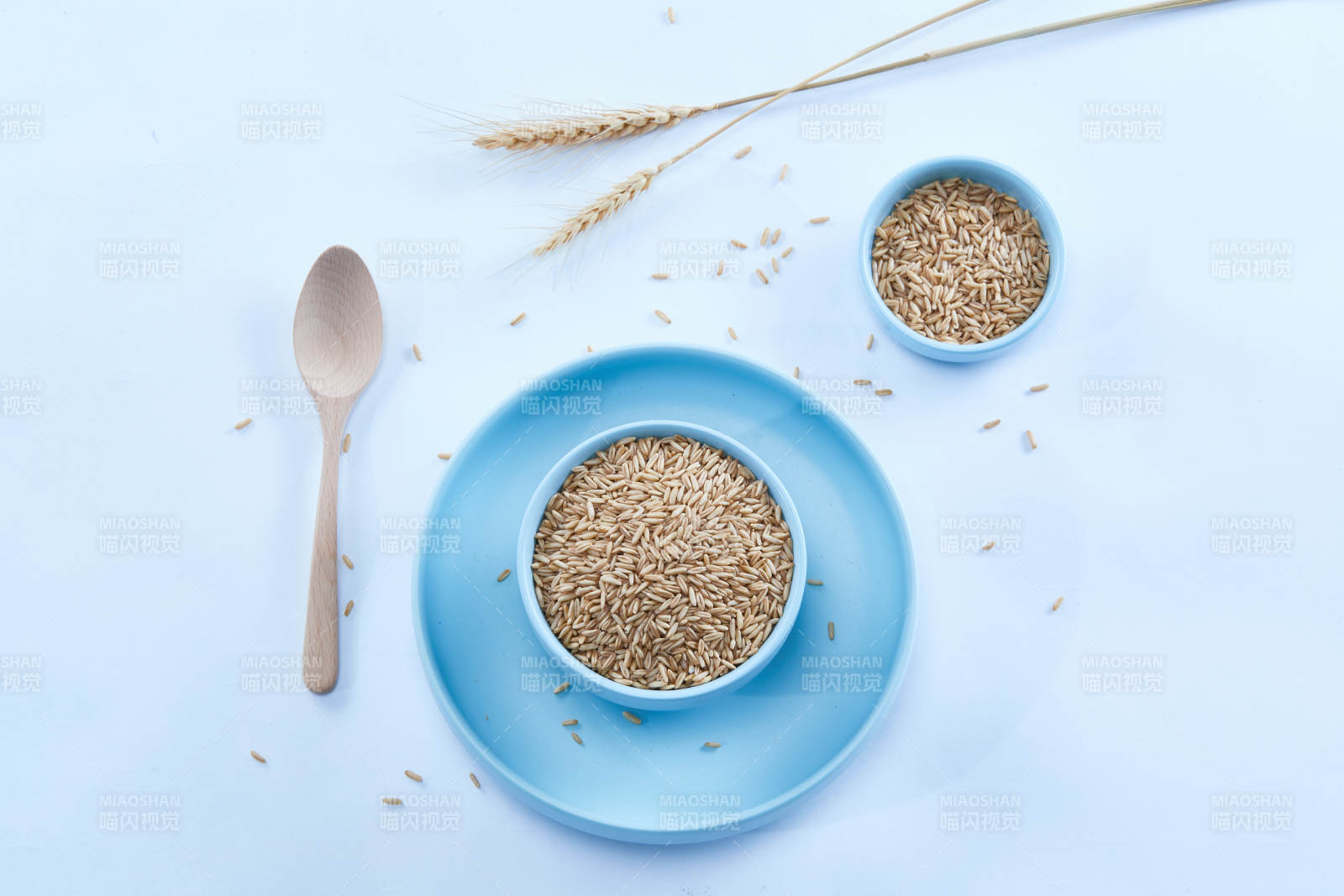 白色纸背景上的青釉瓷餐具及木质餐具装的燕麦米-摄影图