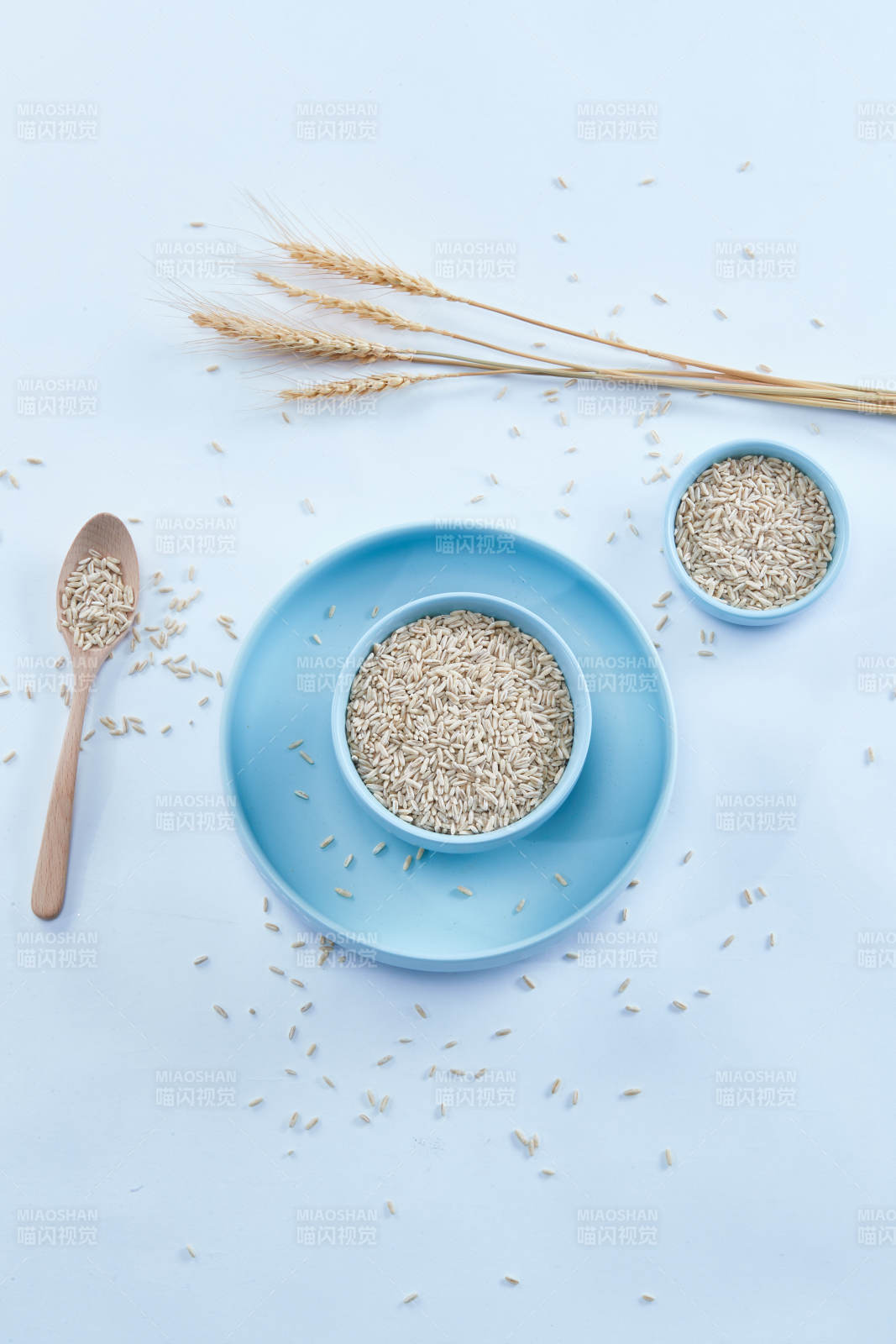 白色纸背景上的青釉瓷餐具及木质餐具装的燕麦米-摄影图