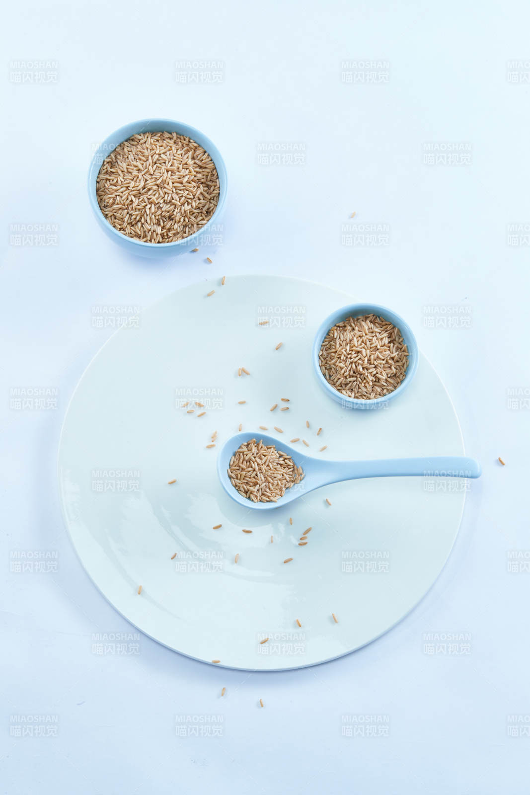 白色纸背景上的青釉瓷餐具及木质餐具装的燕麦米-摄影图