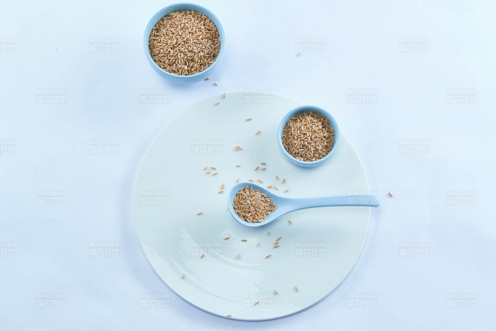 白色纸背景上的青釉瓷餐具及木质餐具装的燕麦米-摄影图