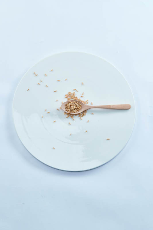 白色纸背景上的青釉瓷餐具及木质餐具装的燕麦米