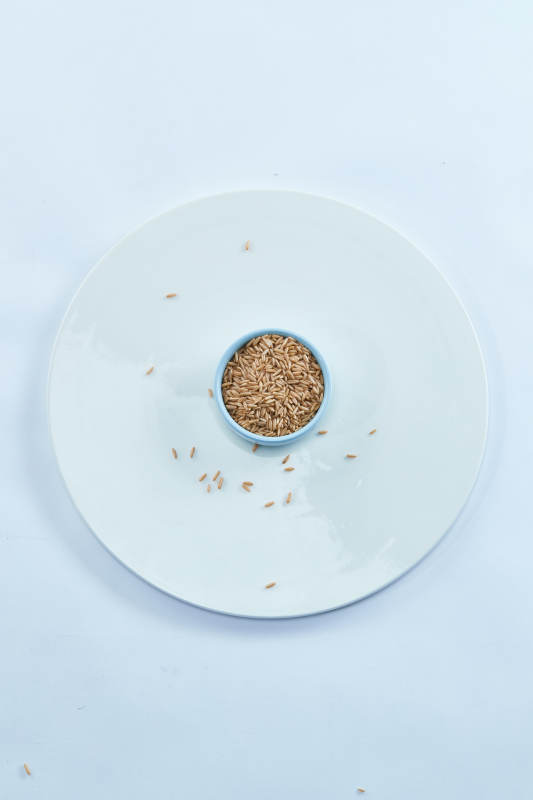 白色纸背景上的青釉瓷餐具及木质餐具装的燕麦米