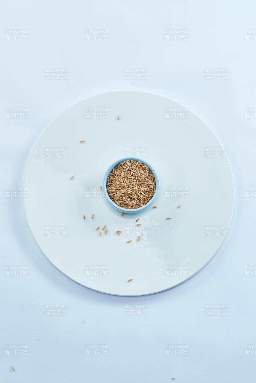白色纸背景上的青釉瓷餐具及木质餐具装的燕麦米