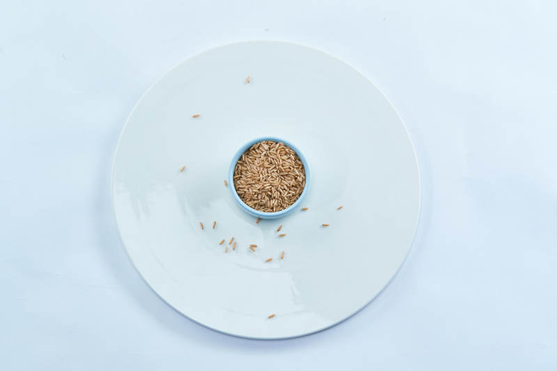 白色纸背景上的青釉瓷餐具及木质餐具装的燕麦米