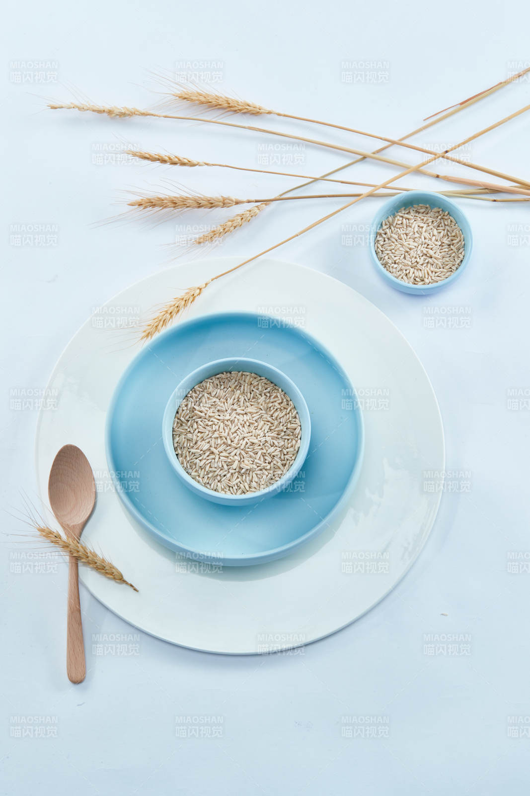 白色纸背景上的青釉瓷餐具及木质餐具装的燕麦米