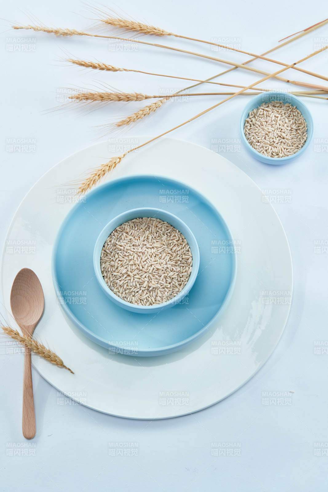 白色纸背景上的青釉瓷餐具及木质餐具装的燕麦米