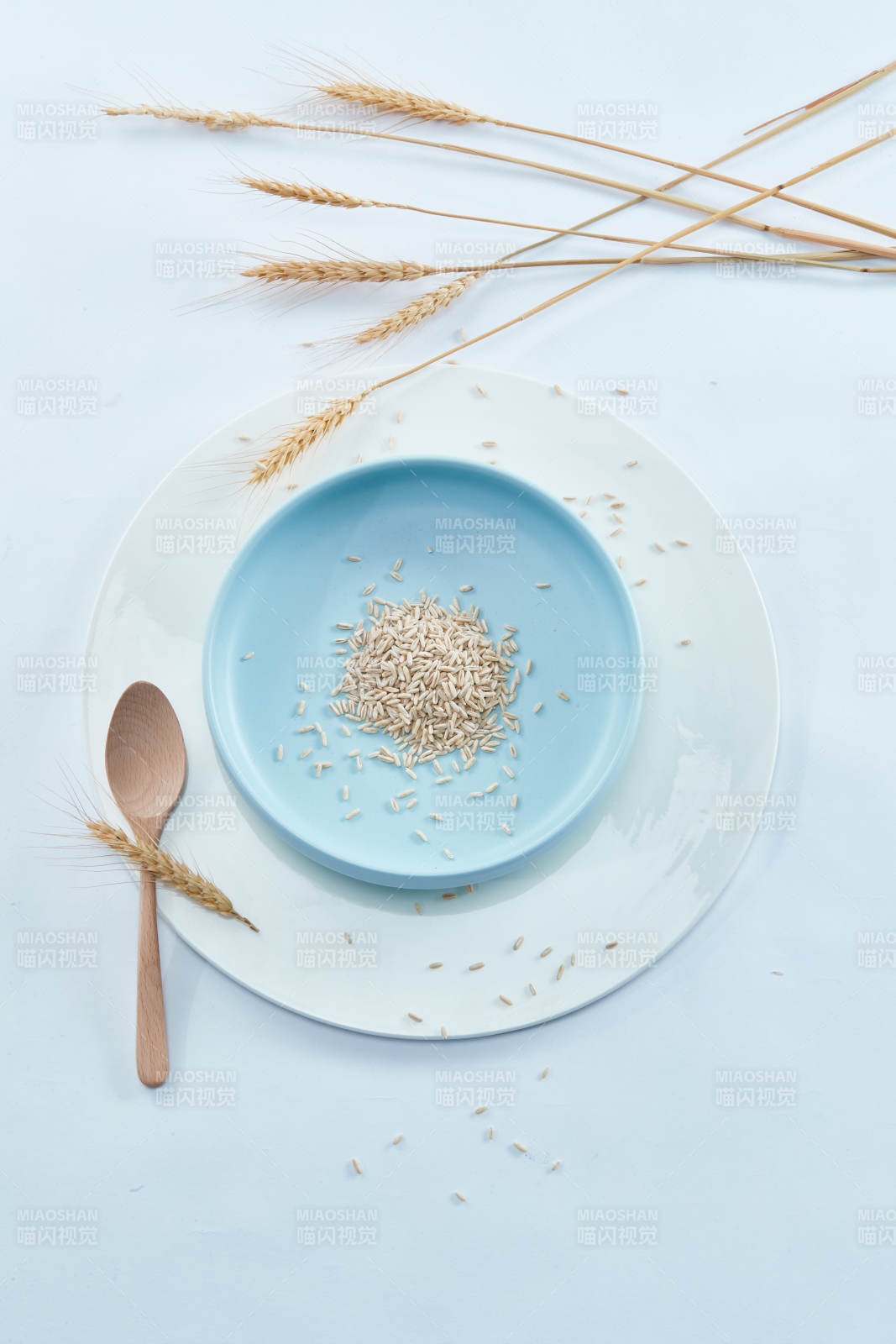 白色纸背景上的青釉瓷餐具及木质餐具装的燕麦米