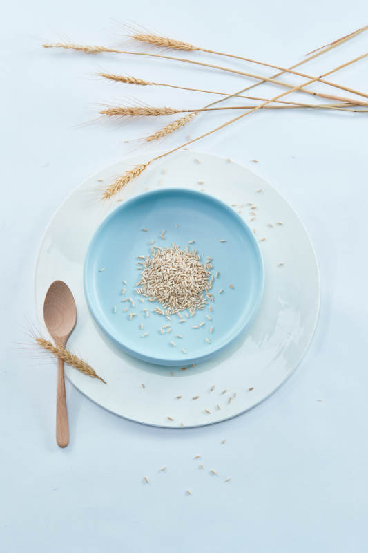 白色纸背景上的青釉瓷餐具及木质餐具装的燕麦米