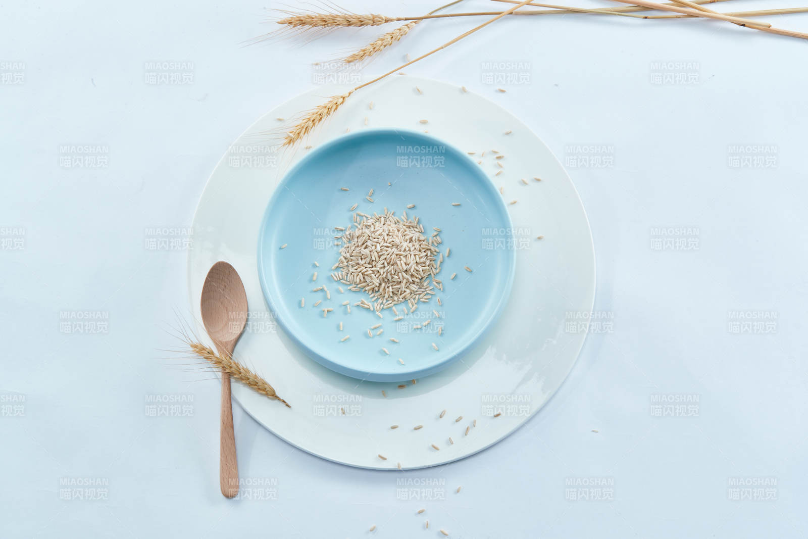 白色纸背景上的青釉瓷餐具及木质餐具装的燕麦米