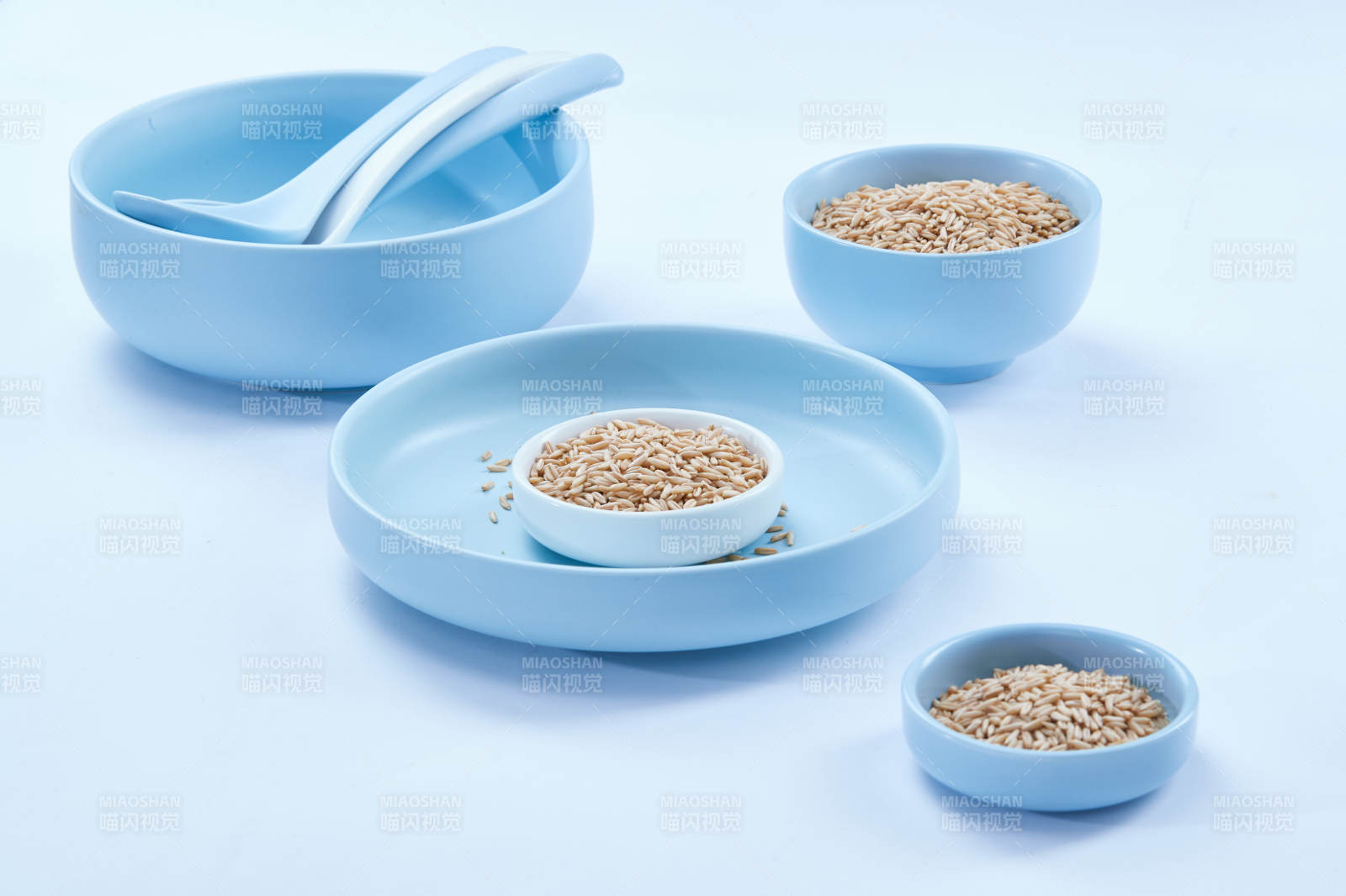 白色纸背景上的青釉瓷餐具及木质餐具装的燕麦米