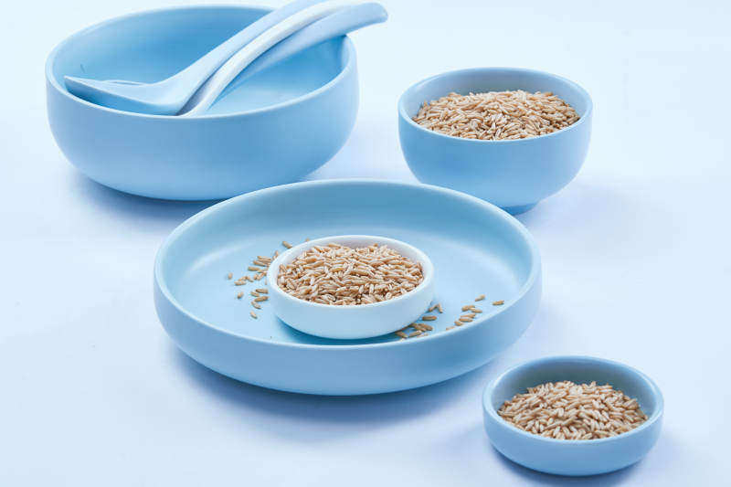 白色纸背景上的青釉瓷餐具及木质餐具装的燕麦米